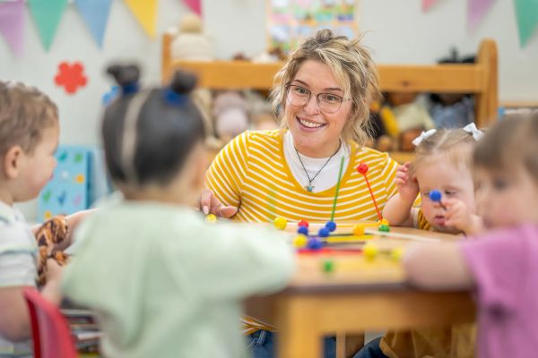  a teacher and several small children sitting at a table playing with tinker toys